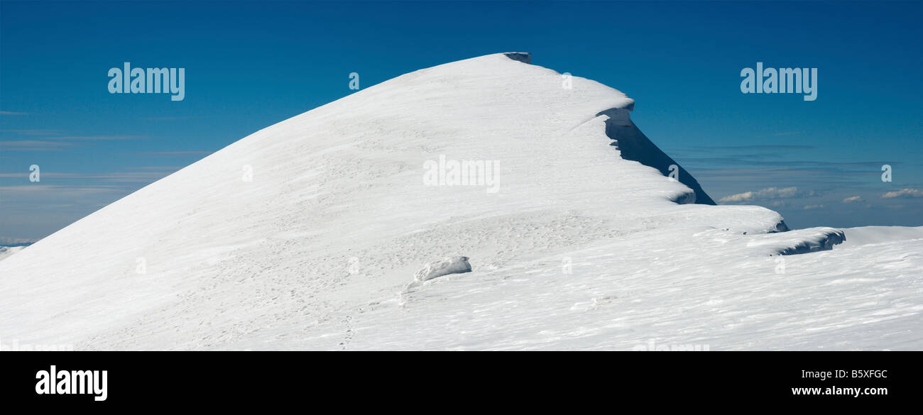Montañas invernales ridge con saliente de nieve y snowboard caps las pistas de fondo de cielo azul Foto de stock