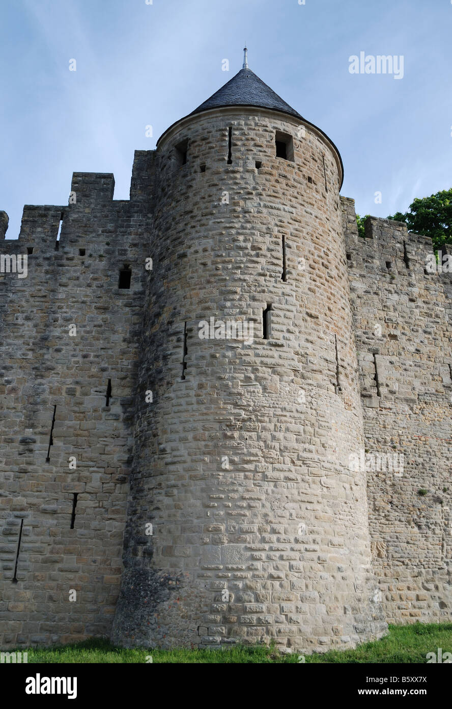Noble torre cónica de la antigua muralla defensiva con lagunas y mampostería irregular contra el cielo azul Carcasson castillo Foto de stock