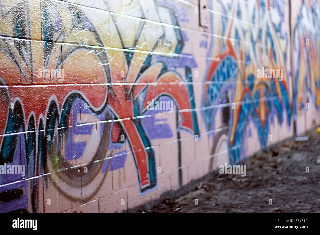Colorido graffiti pintado con spray en una pared de ladrillo hace un excelente telón de fondo o profundidad de campo Foto de stock
