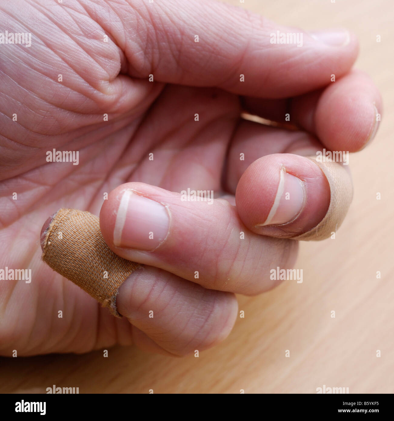Una mano de trabajador torpe con tiritas de bandolera en los dedos lesionados Foto de stock