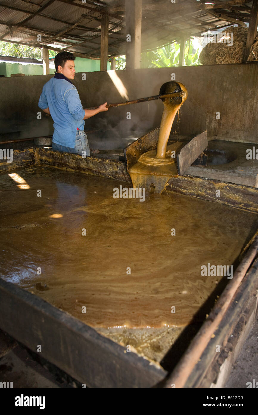 La caña de azúcar, un trabajador transfiere la melaza de azúcar en un pilón de piedra para enfriar, Venezuela, Sudamérica Foto de stock