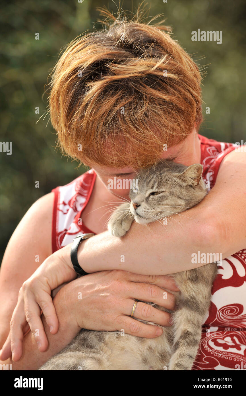 Gato atigrado gris smooching joven con una mujer Foto de stock