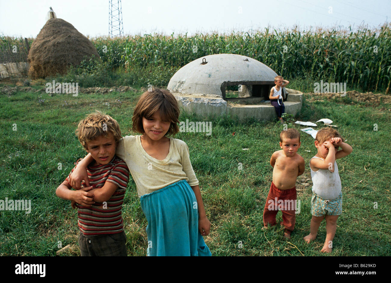 Los niños están junto a uno de los numerosos cuadros de píldora de defensa militar que pueblan el campo, cerca de Tirana, Albania 1992 Foto de stock