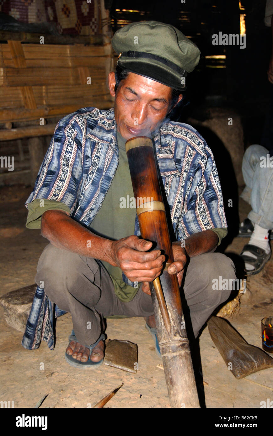 Un hombre laosianos de la etnia Phunoi llevaba una gorra y el hábito de fumar una pipa de agua Bong, Ban Khounoum Phongsali Louang, Pro Foto de stock