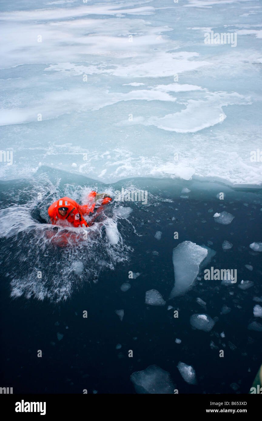 El hombre en traje de supervivencia saltando de las placas de hielo en el agua del Ártico Foto de stock