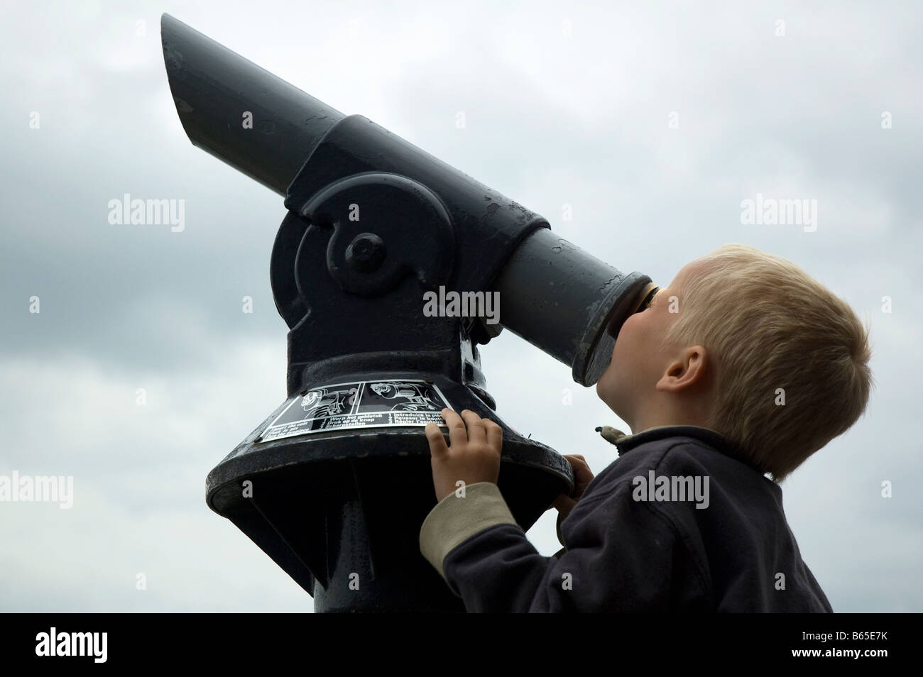 Niño mirando hacia el cielo a través de un telescopio Foto de stock