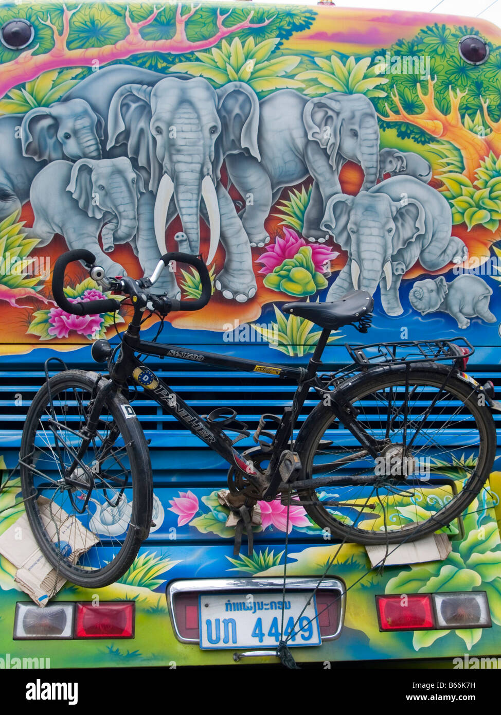 Bicicleta en la parte de atrás de un autobús con un colorido mural entre Luang Prabang y Vientiane en Laos Foto de stock
