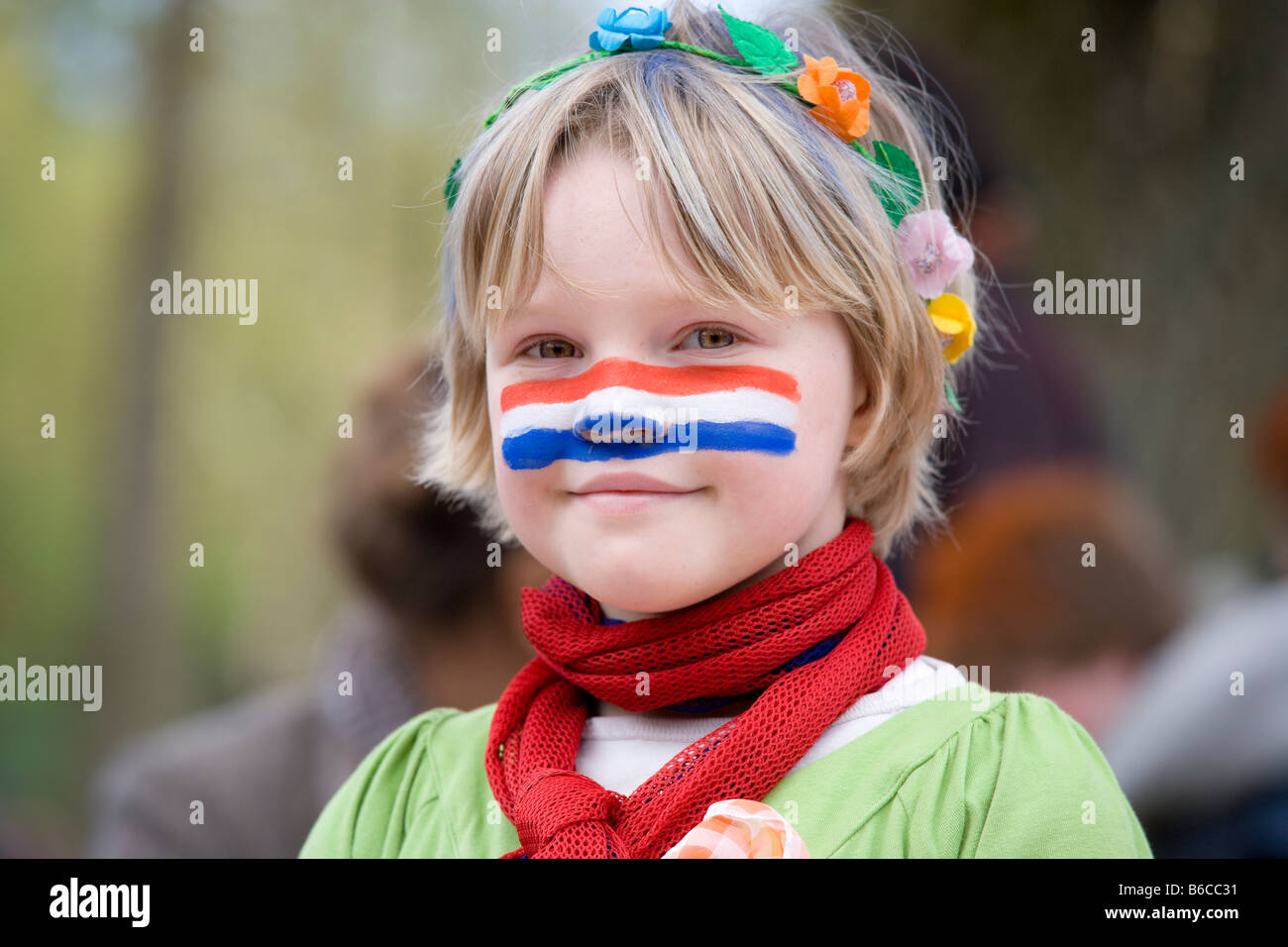 Chica con bandera holandesa sobre la pintura facial (Queensday Kingsday) Reyes Magos, fiestas de cumpleaños del Rey en Amsterdam Holanda Holanda bandera. Foto de stock