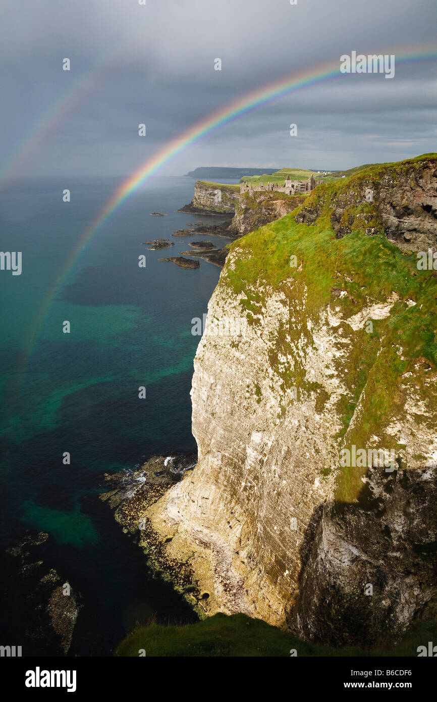 Un doble arco iris sobre los acantilados de rocas blancas y vista hacia el Castillo de Dunluce en la costa del norte de Antrim, Irlanda del Norte Foto de stock