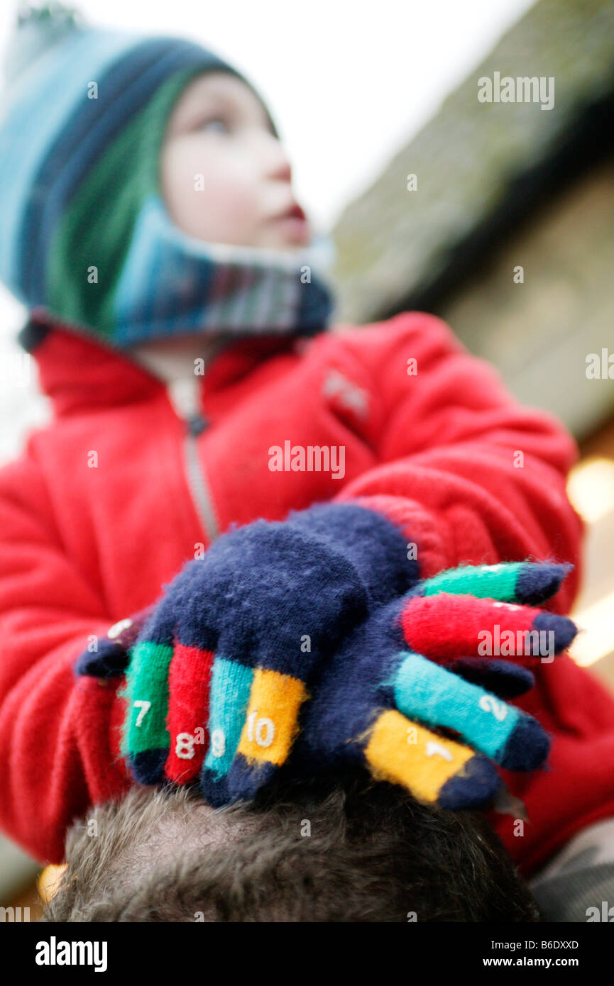 Niño con los guantes puestos. Hijo sentado sobre los hombros de un adulto,  llevar guantes de invierno Fotografía de stock - Alamy
