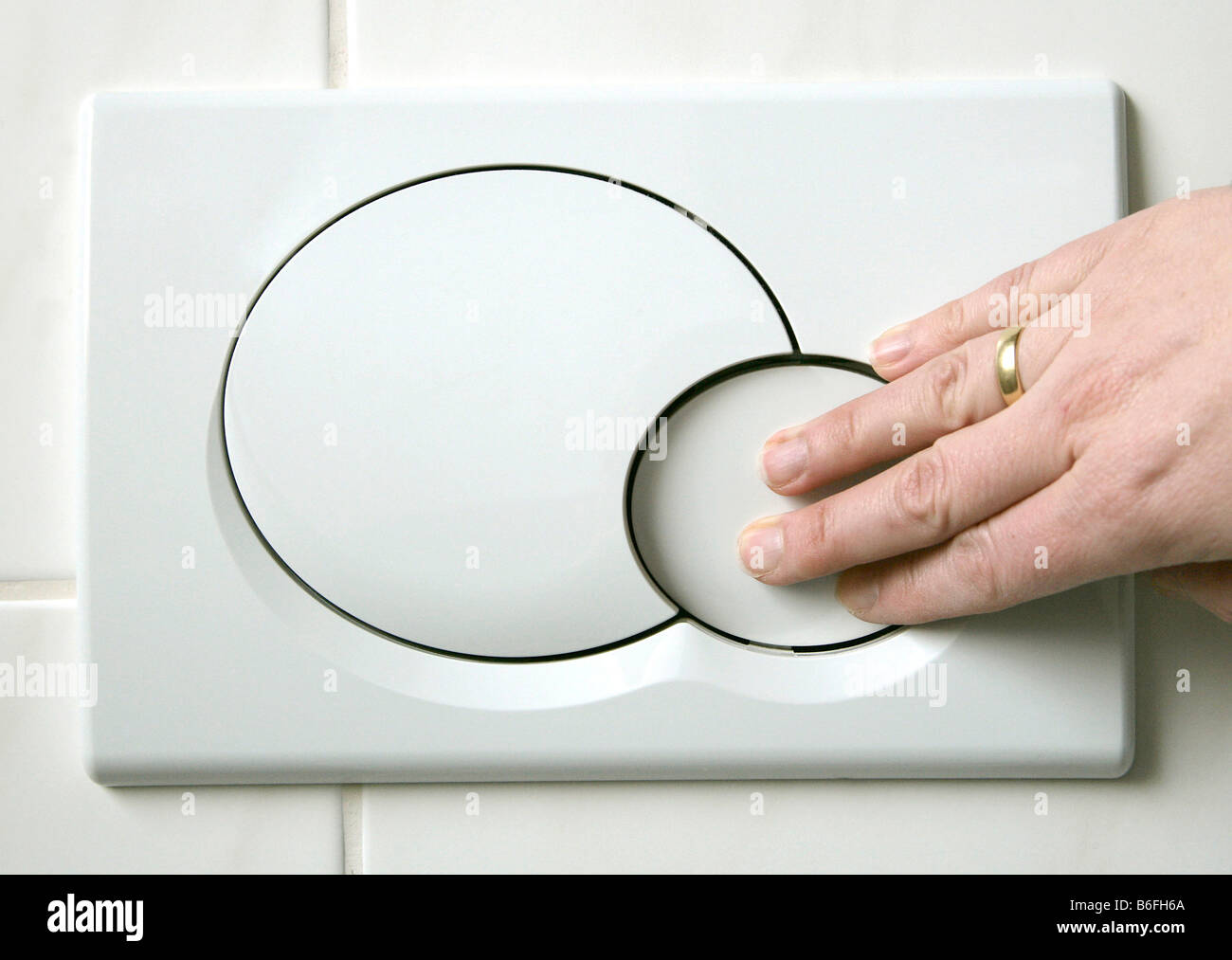 Mano empujando el botón empotrado bajo un botón dos retretes sistema, diseñado para reducir el uso del agua, Ratisbona, Baviera, Foto de stock