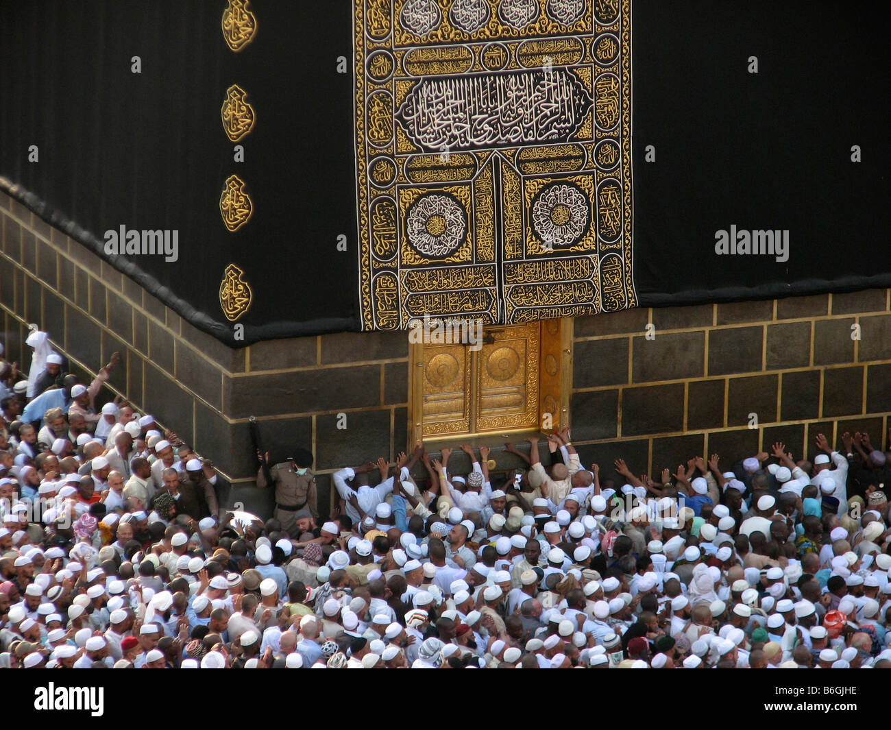 Peregrinos musulmanes alineándose contra la pared y la puerta de El Kaba Makkah Arabia Saudita durante el Hajj en 2007 Foto de stock