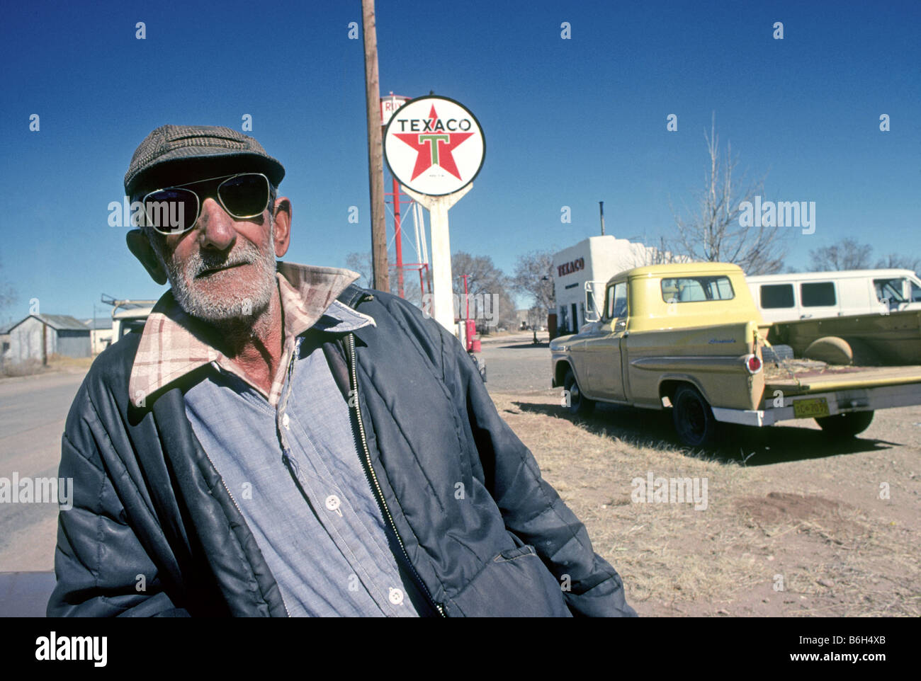 Un Mew 96 años hombre hispano mexicana con gafas de sol y necesitar un afeitado y su anciano camioneta Foto de stock