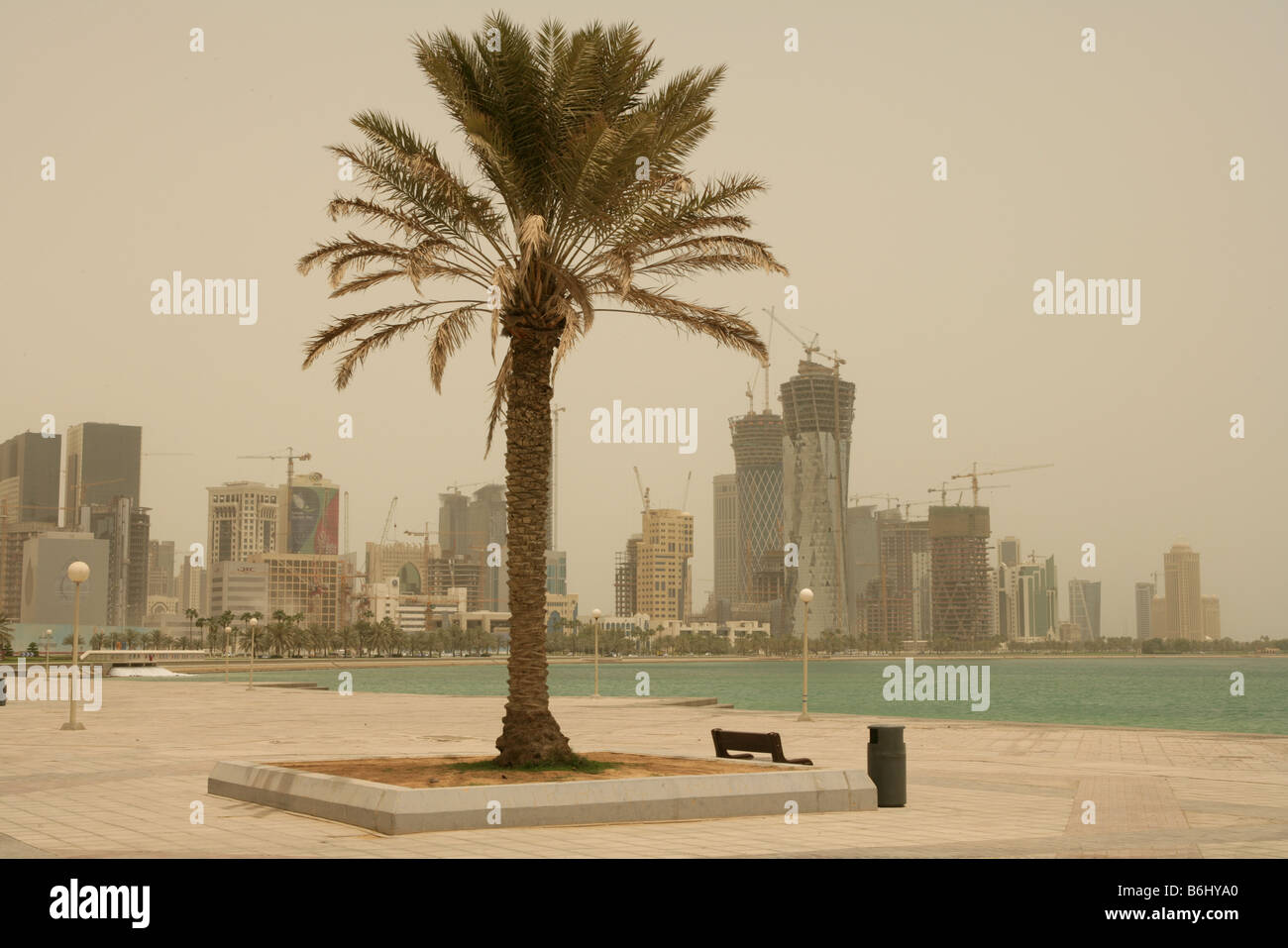 Vista panorámica a lo largo de la Corniche, el paseo marítimo con la construcción de grúas en el horizonte de rascacielos, Doha, Qatar, Oriente Medio Foto de stock