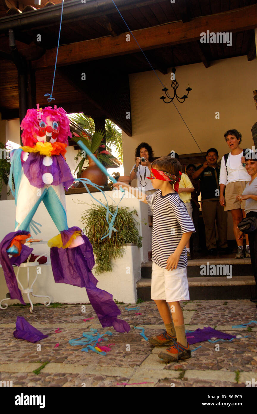 Un niño con los ojos vendados va a romper una celebración de cumpleaños de  piñata accesorios y regalos brillantes