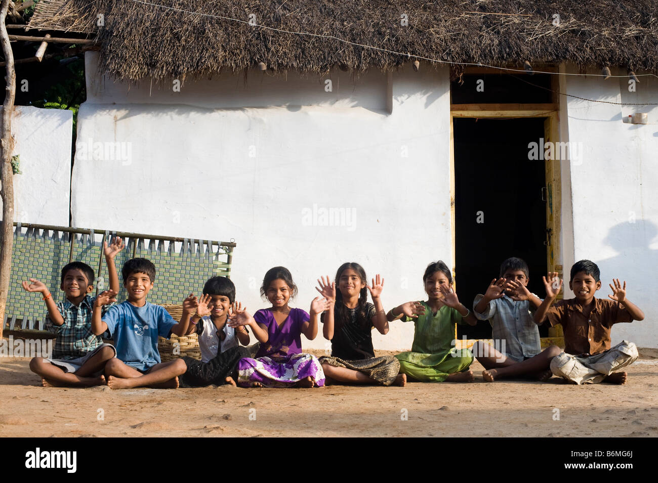Los niños indios sentados en una fila ondeando divirtiéndose fuera una  aldea rural casa. En Andhra Pradesh, India Fotografía de stock - Alamy