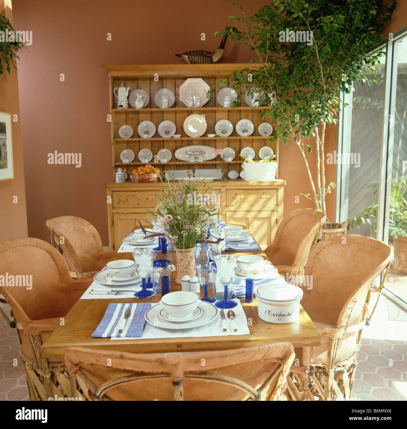 Sillones de cuero neutral estilo Mexicano en la mesa para el almuerzo en el  comedor de terracota con altos houseplant y gran armario Fotografía de  stock - Alamy