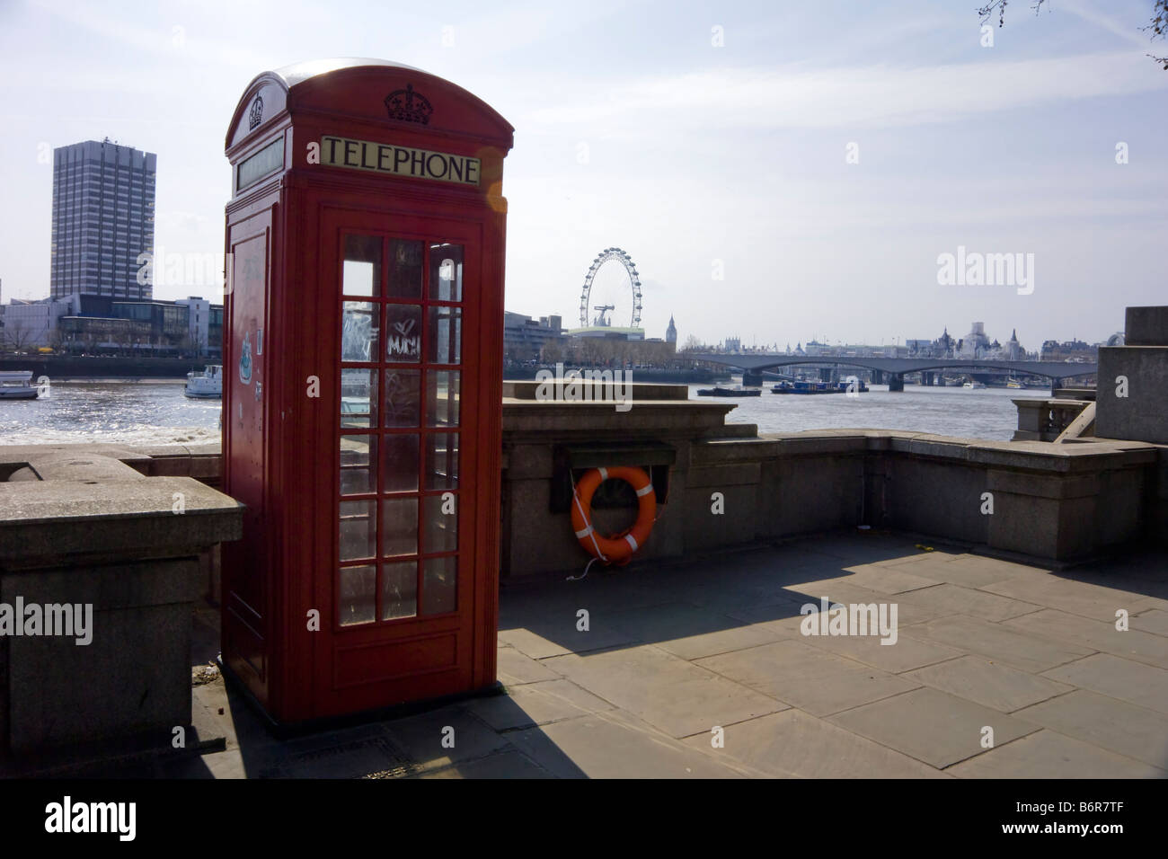 Cuadro teléfono rojo tradicional británico a lo largo del terraplén norte del Támesis con el London Eye más allá. UK Foto de stock