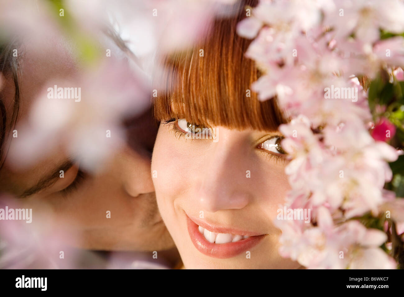 Besos joven mujer bajo un árbol floreciente Foto de stock