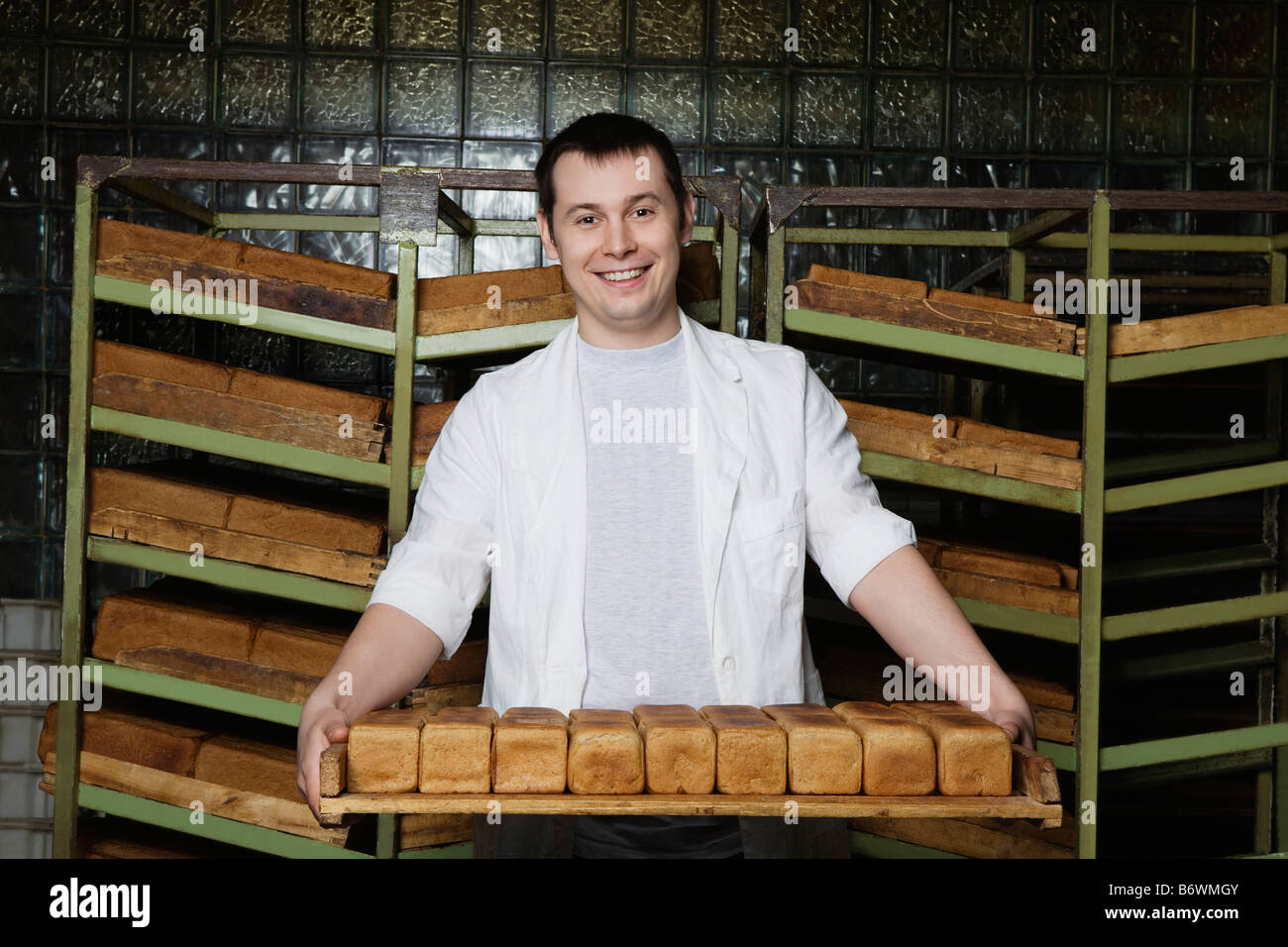 Baker llevando hogazas de pan fresco Foto de stock