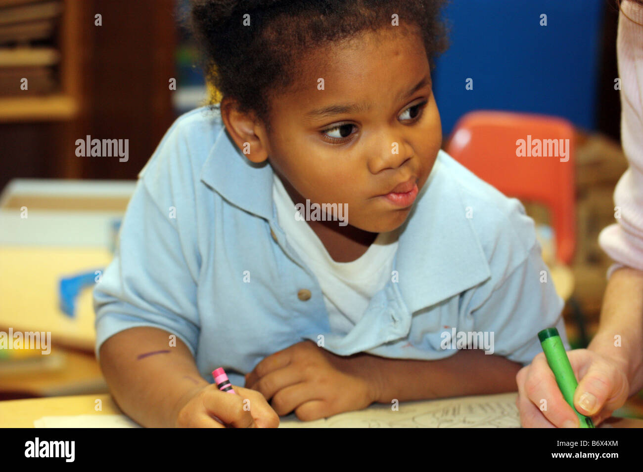 Jóvenes Africanos American Girl colorear imágenes con lápices de colores sobre un escritorio Foto de stock