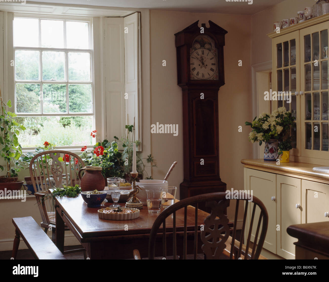 Reloj en país pequeño comedor con mesa de madera y sillas de Fotografía de stock - Alamy