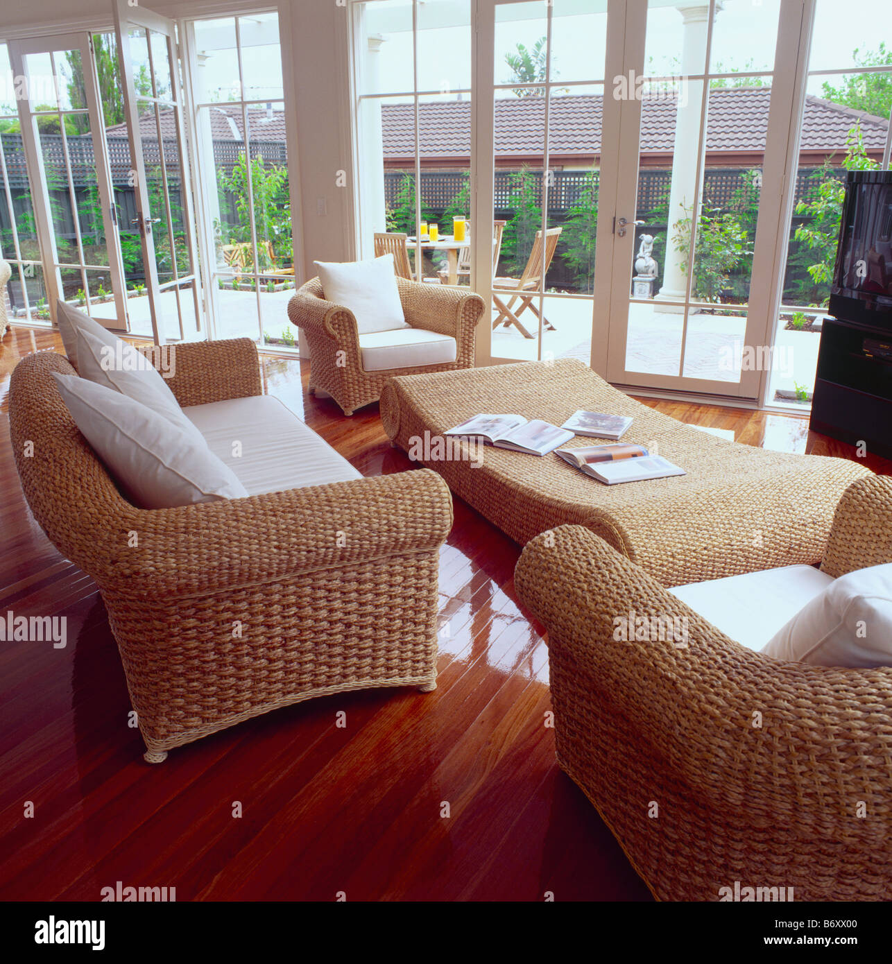 Sofás y sillones de mimbre con cojines blancos en conservatorio moderno  salón con mesa de café de mimbre larga Fotografía de stock - Alamy