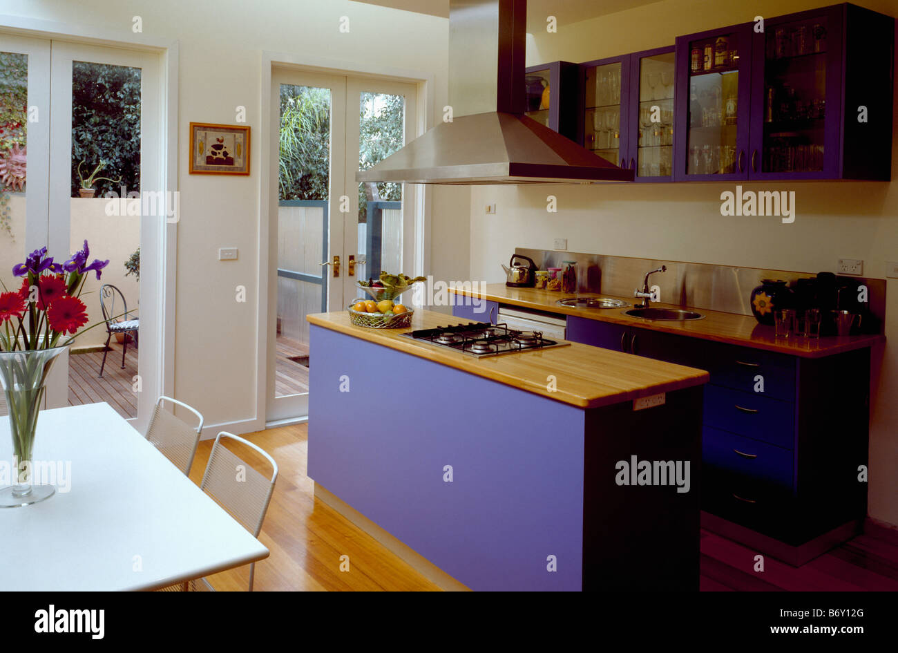 Encimera de madera en blue island en unidad openplan moderna cocina comedor  con puertas francesas y vista del patio decorado Fotografía de stock - Alamy
