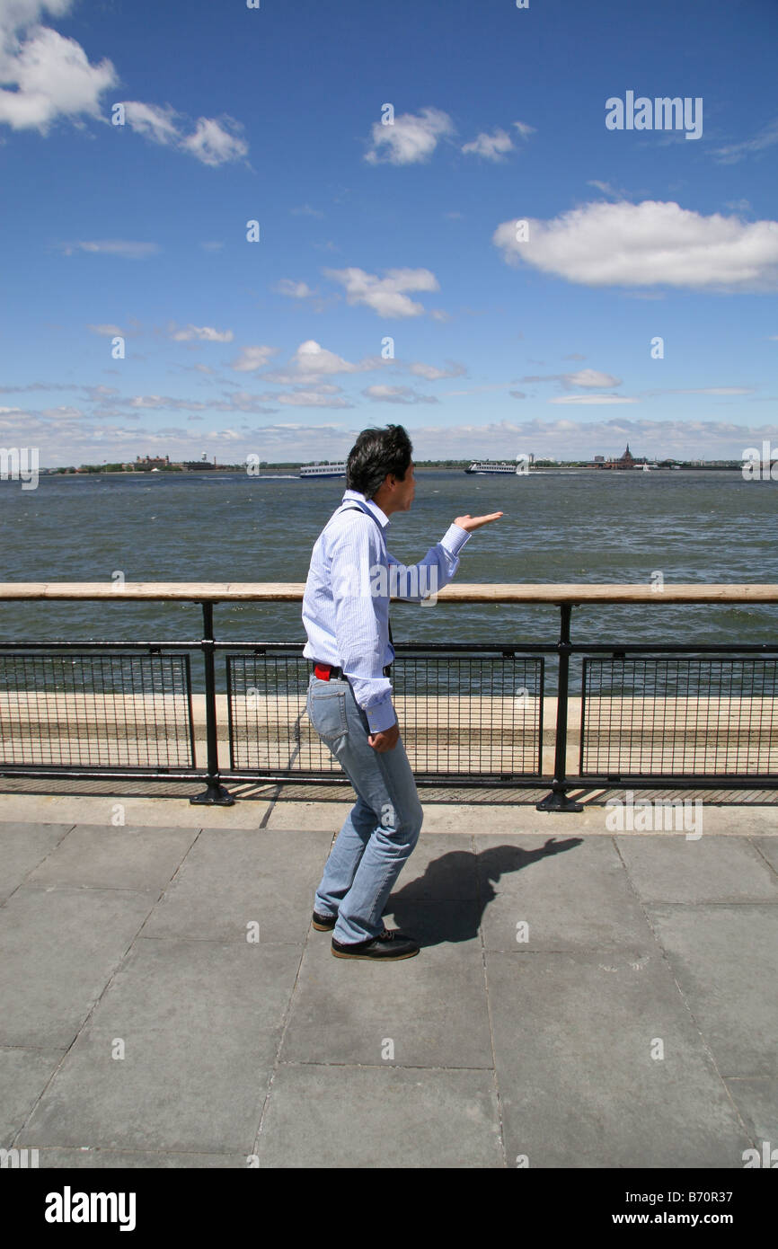 Un turista asiático posan para una fotografía simulando para sujetar la estatua de la libertad en Battery Park, Nueva York. Foto de stock