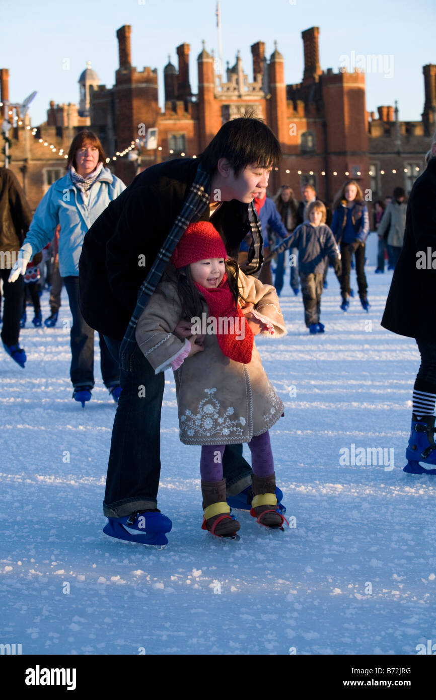 Hombre sujetando a su hija mientras aprende a patinar, en Hampton Court Palace una pista de patinaje sobre hielo. Hampton Court Palace. UK Foto de stock