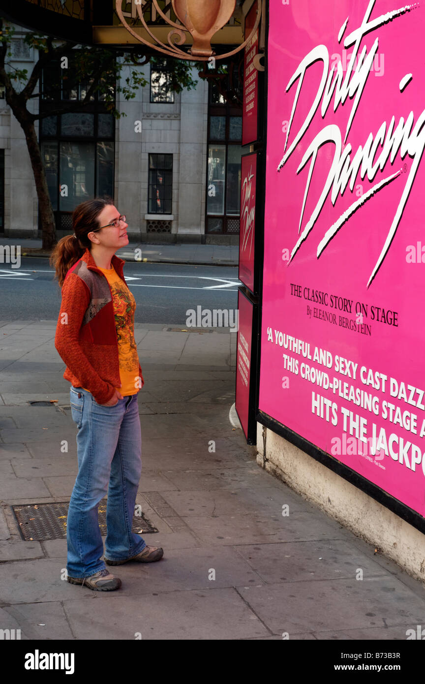 Una joven mujer mirando un gran cartel de la representación teatral de "Dirty Dancing" Foto de stock