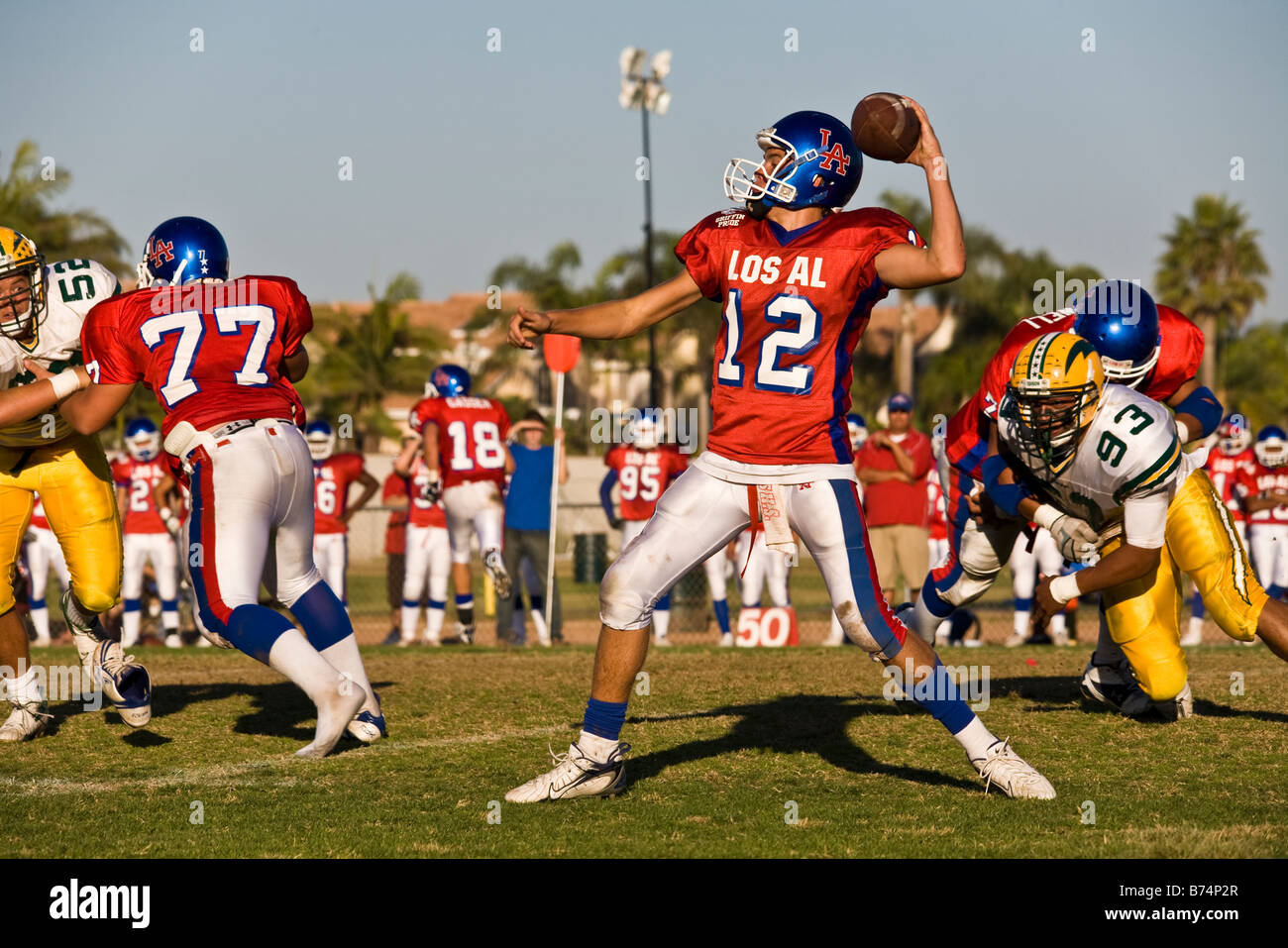 Un jugador lanzando el balón en un partido de fútbol americano con futbolistas corriendo alrededor, Huntington Beach, California, EE.UU. Foto de stock