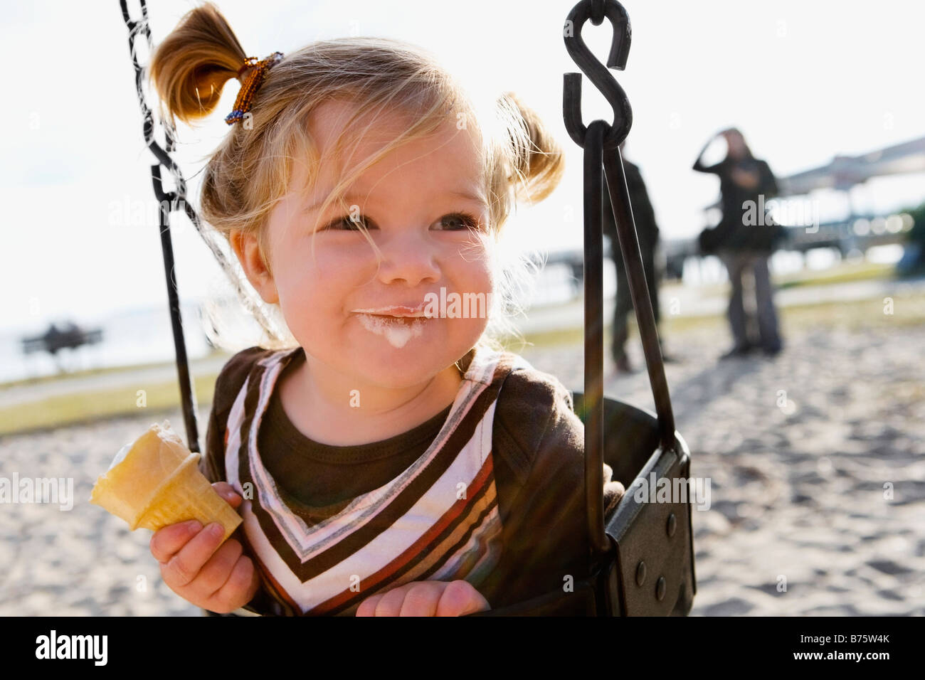 Close-up de una niña sentada en un columpio cadena ride y comiendo un  helado Fotografía de stock - Alamy