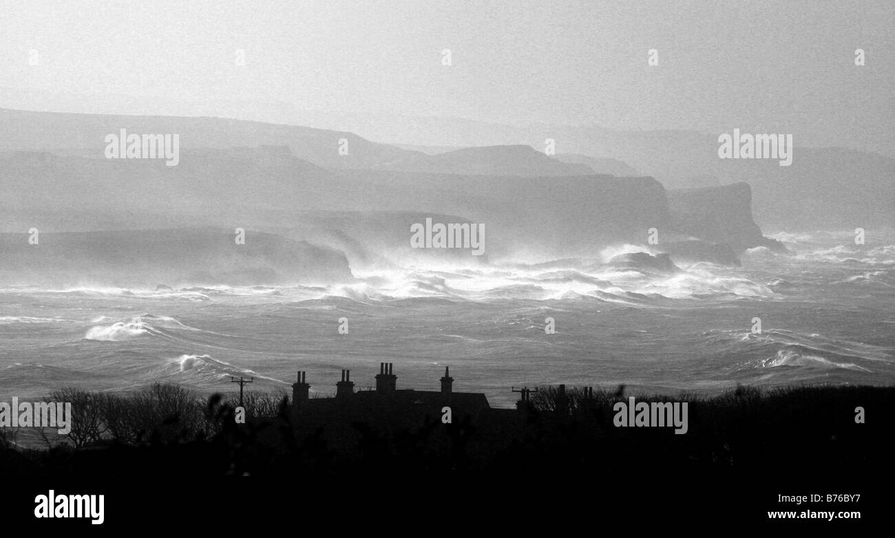 Una imagen monocroma de una vista de las olas rompiendo en la costa del Condado de Antrim, Irlanda del Norte en otoño Foto de stock