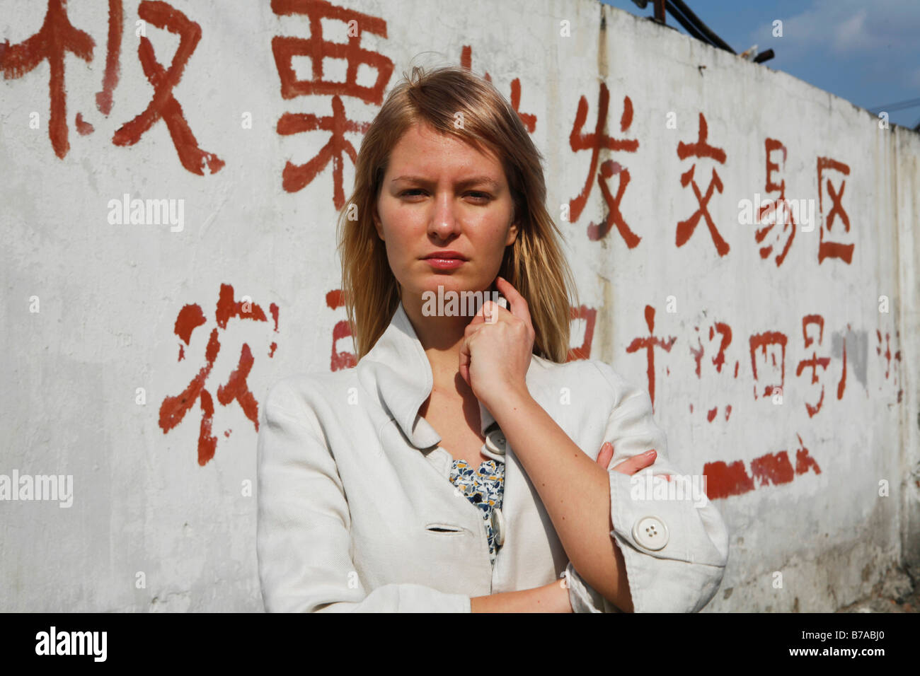 Mujer joven delante de una pared con letras chinas sobre ella Foto de stock