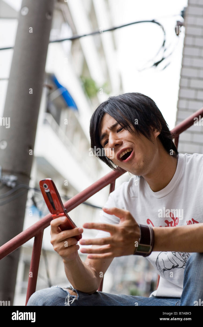Joven jugando un juego en un teléfono móvil, Tokio, Japón, Asia Foto de stock