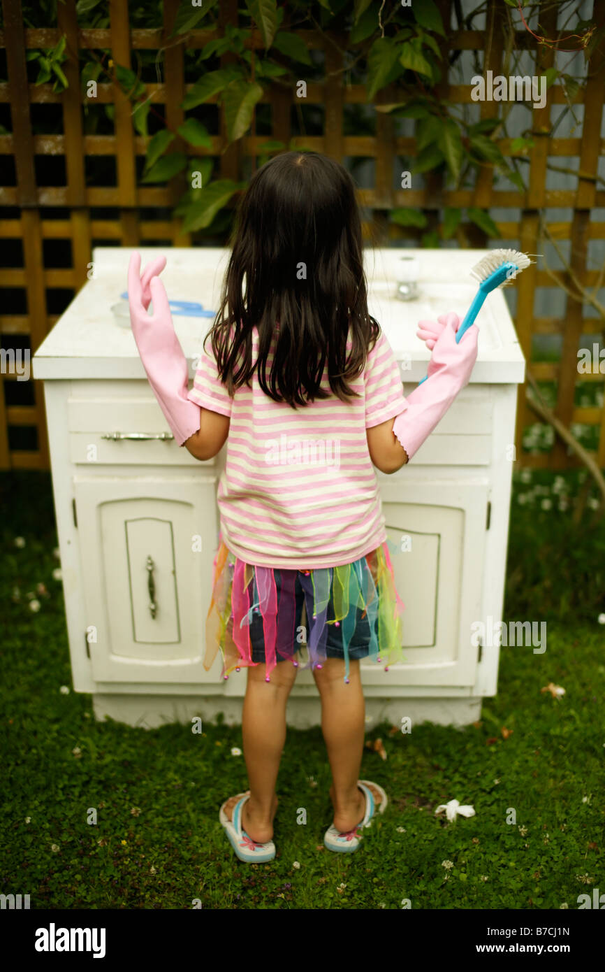 Niña de seis años juega en el lavado en antiguas fregadero en el jardín Foto de stock