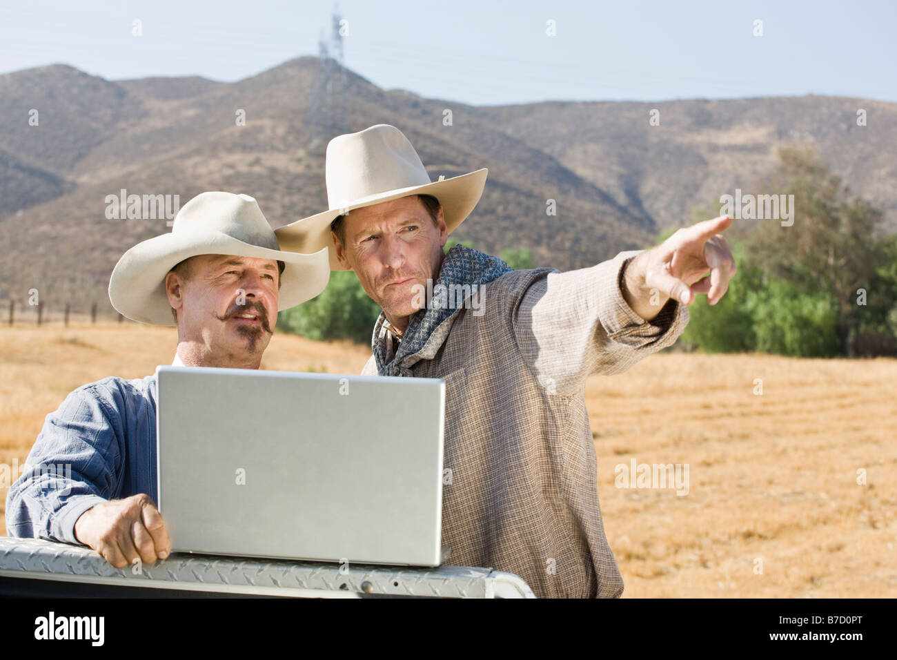 Dos vaqueros usando un ordenador portátil y apuntando Foto de stock