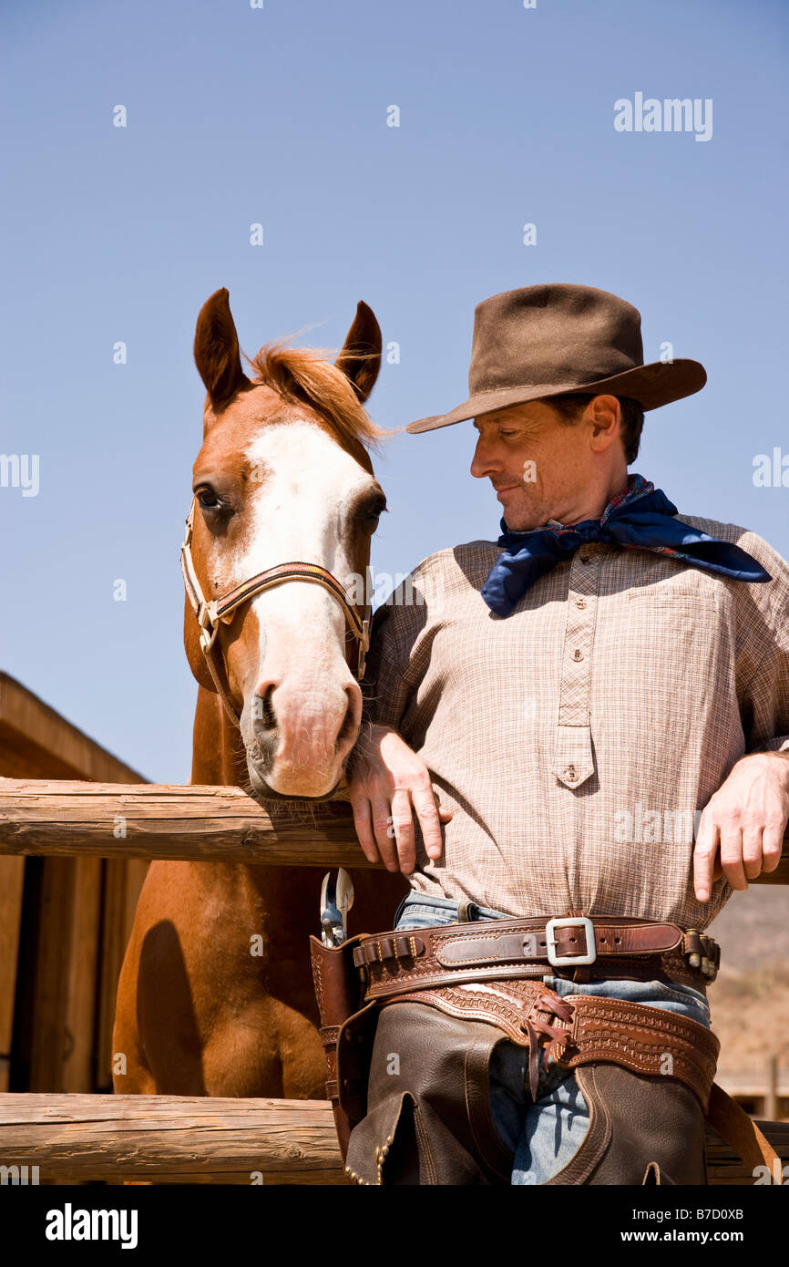 Retrato del vaquero de pie junto a un caballo Foto de stock