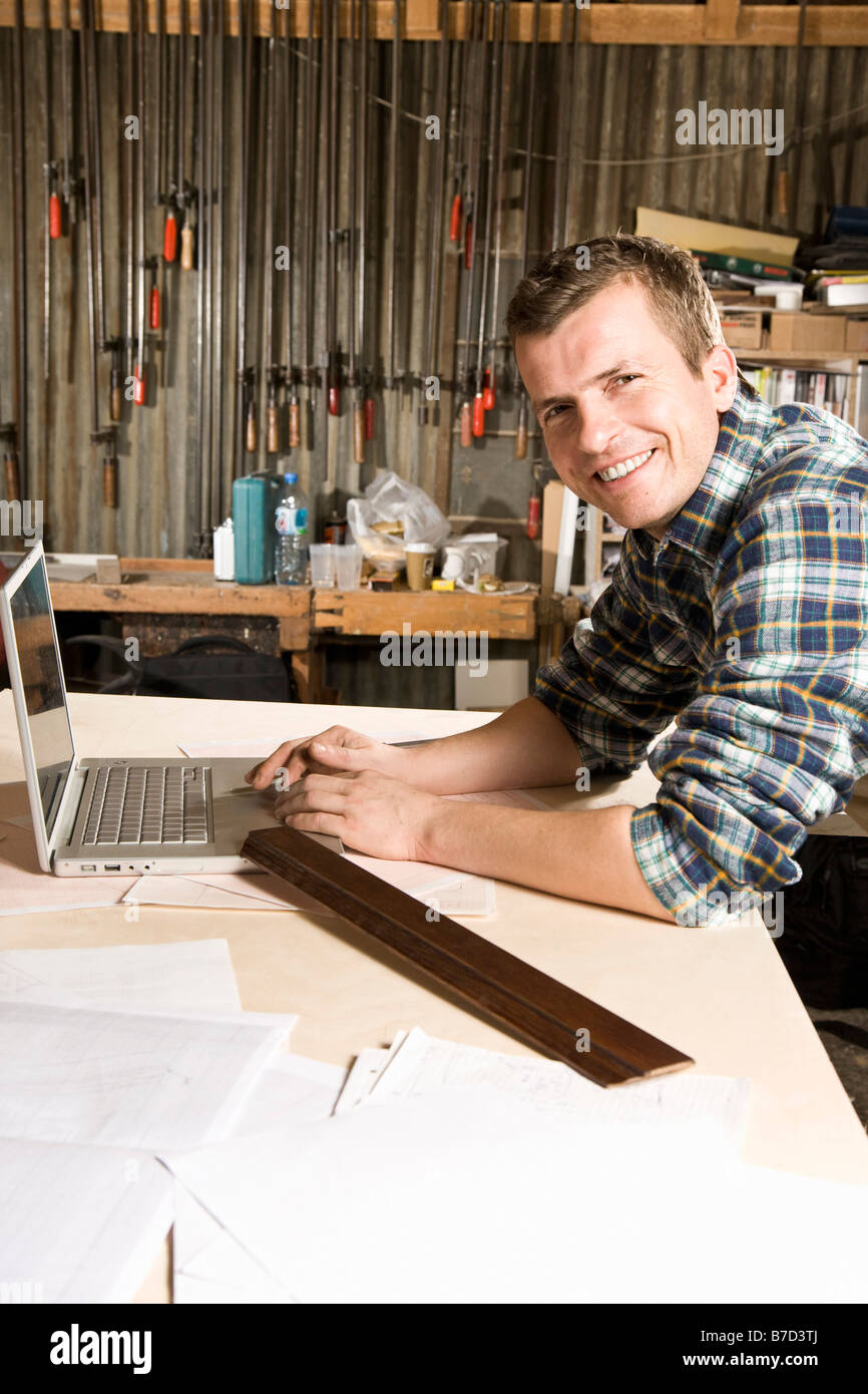 Retrato de un carpintero utilizando un ordenador portátil en un taller Foto de stock