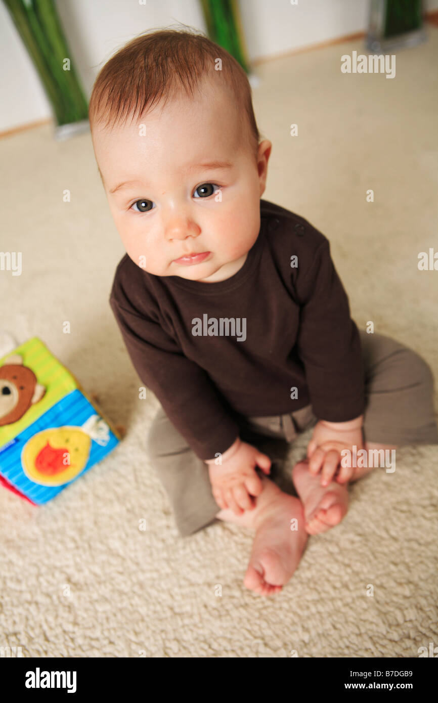 Bebé de 4 meses de edad sentado con los pies descalzos sobre una