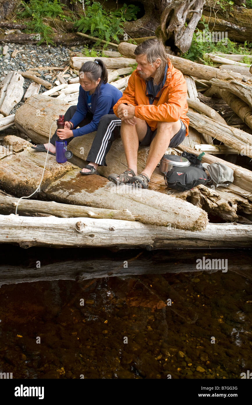 BRITISH COLUMBIA - Padre e hija, filtración de agua de un arroyo de agua fresca en el Nissen Bight en el sendero de la costa norte. Foto de stock