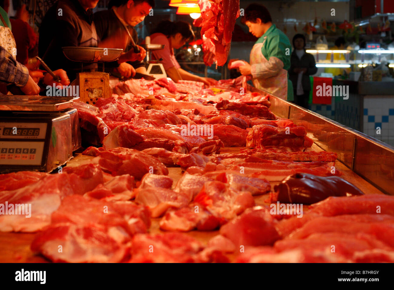 Carniceros chinos en el mercado local de carne de corte Foto de stock