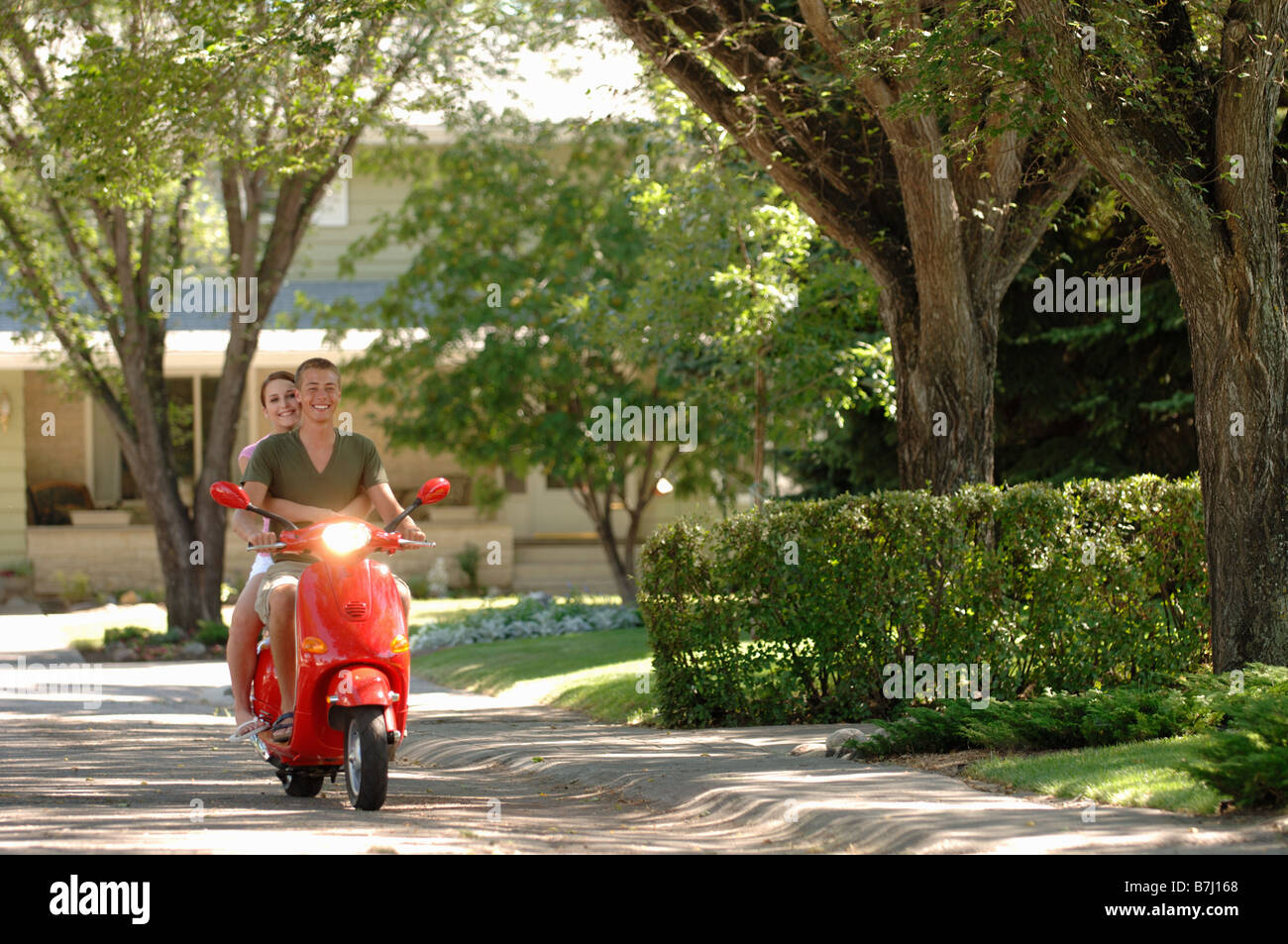 Chico y chica adolescentes conducción minimoto Vespa roja, Regina, Saskatchewan Foto de stock
