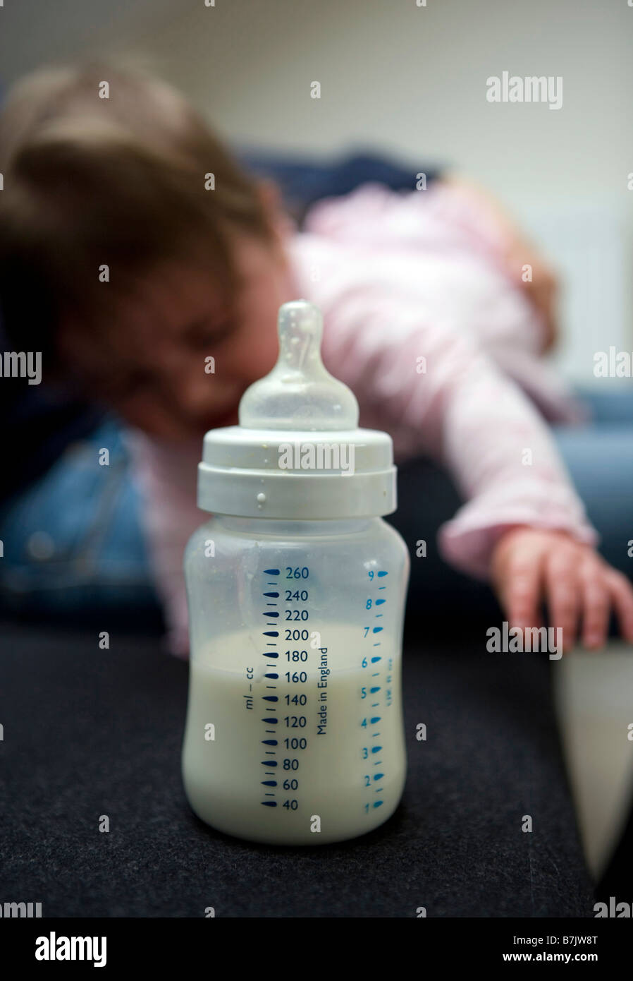 Una niña alcanza su botella de leche Foto de stock