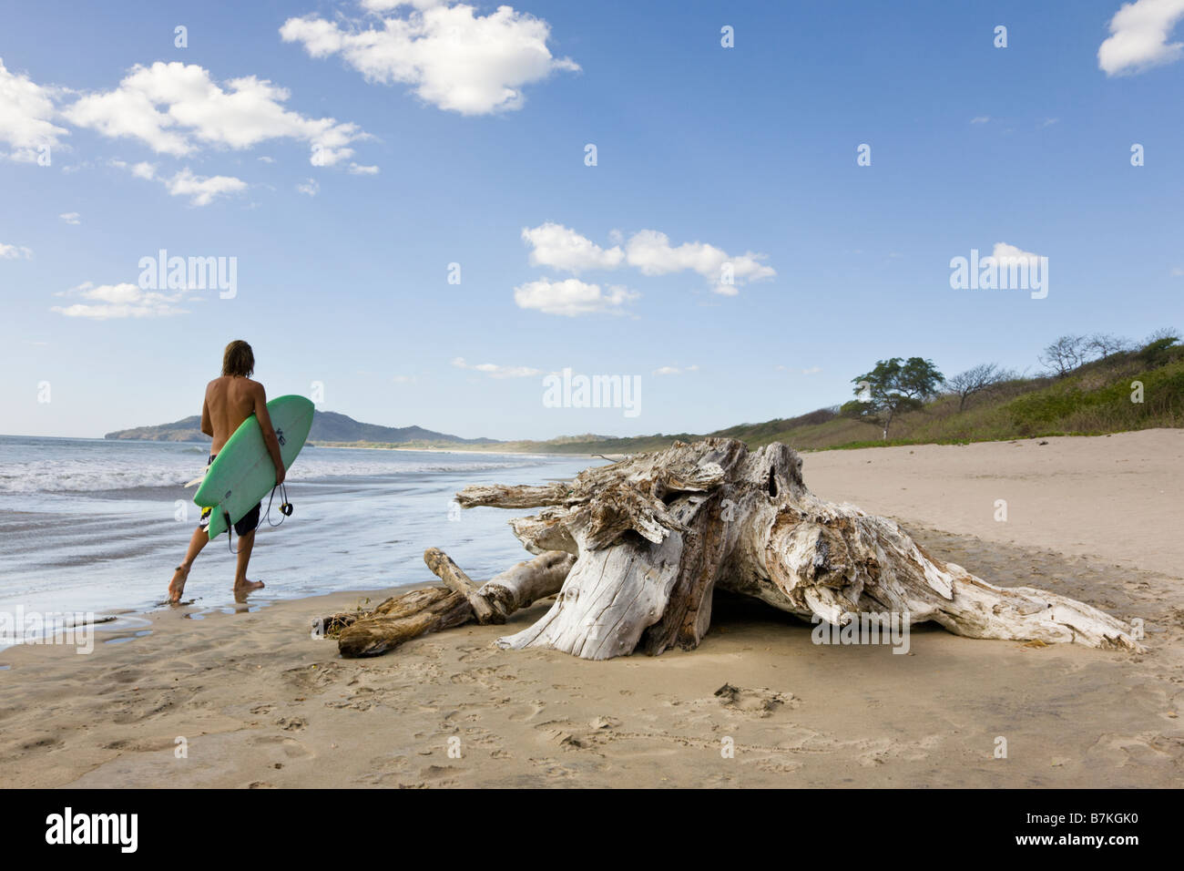 Surfer caminando sobre la orilla de la Playa Grande en Costa Rica. Foto de stock