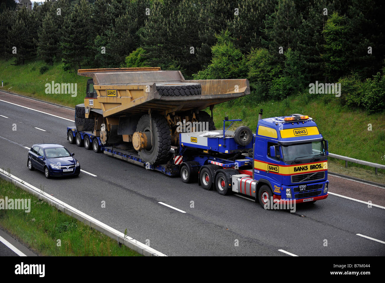 Los bancos Volvo FH transporte pesado camión que transportaba un camión volquete gigante amplia carga anormal en la autopista Foto de stock