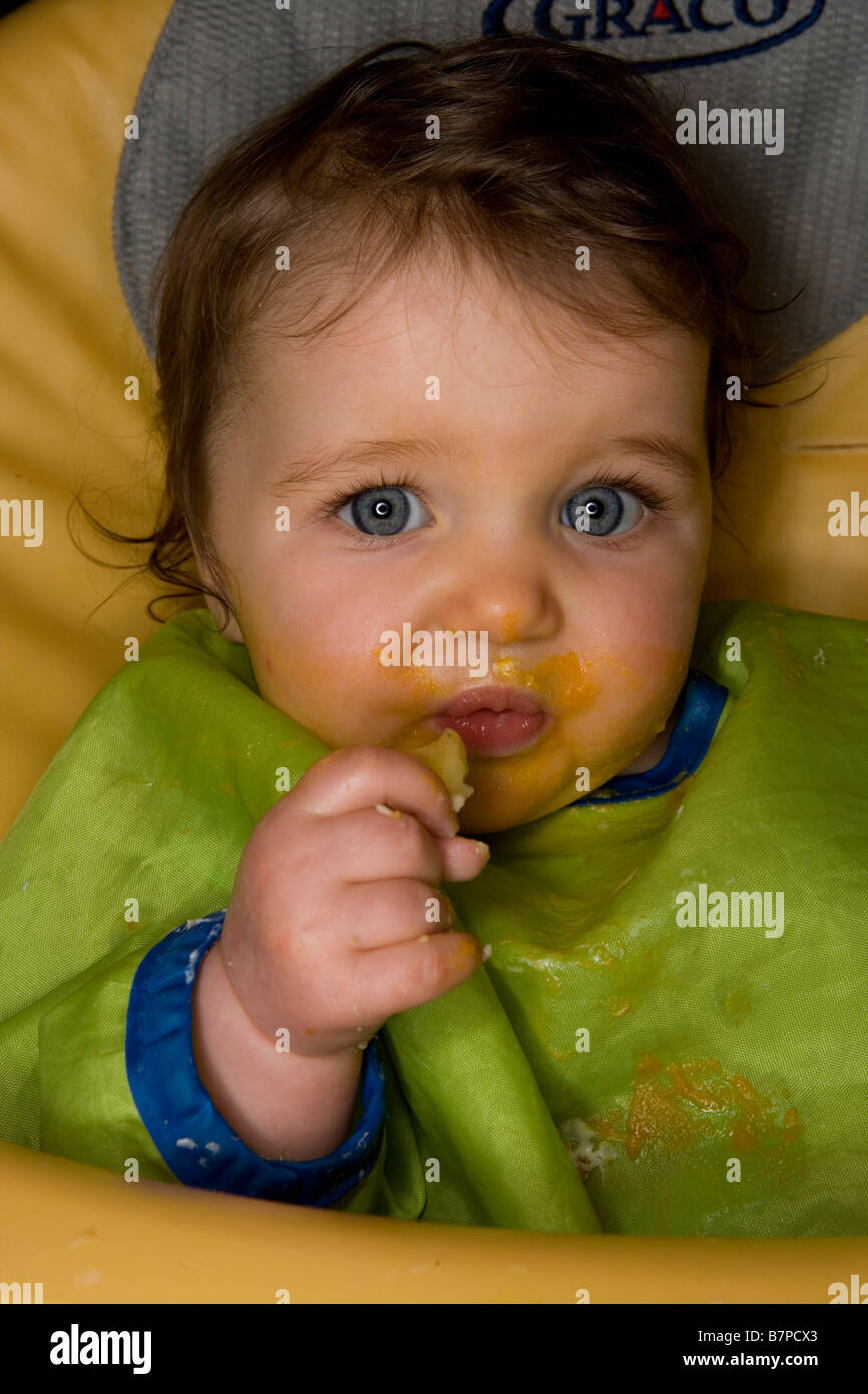 Un bebé de 8 meses chica con finger food a la hora de la comida Foto de stock