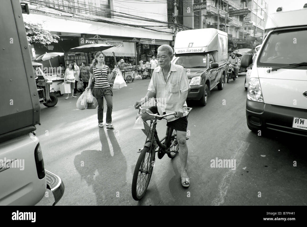 Hombre en bicicleta atascado en el tráfico Chinatown Bangkok Thailand Foto de stock