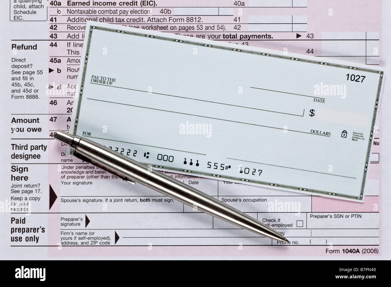 Un cheque en blanco con un bolígrafo en varios formularios de impuestos Foto de stock